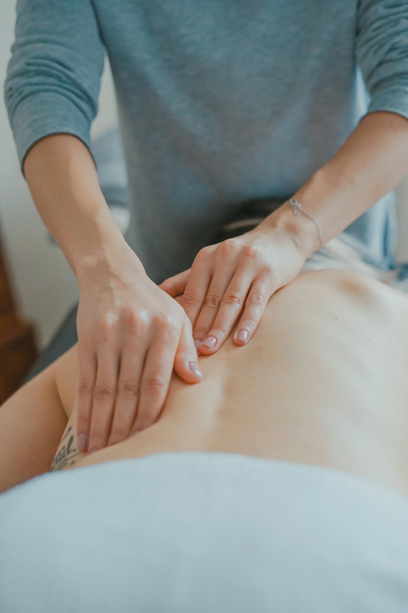Manos de un kinesiólogo trabajando sobre la espalda de un paciente